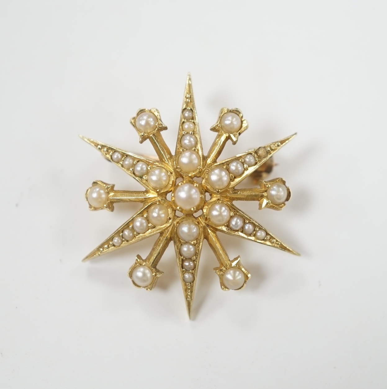 An Edwardian 15ct and split pearl cluster set starburst brooch, 29mm, gross weight 5.5 grams.